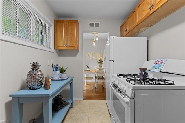 kitchen with visible vents, white appliances, and brown cabinetry