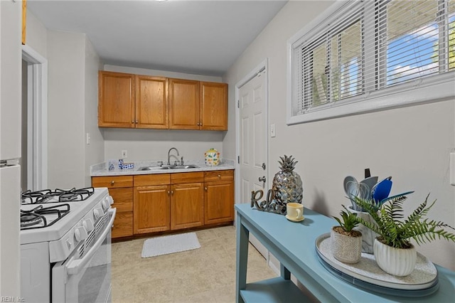 kitchen featuring gas range gas stove, plenty of natural light, light countertops, and a sink
