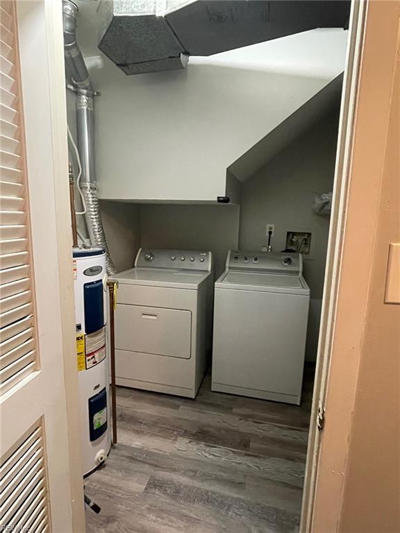 washroom featuring laundry area, washing machine and dryer, wood finished floors, and water heater
