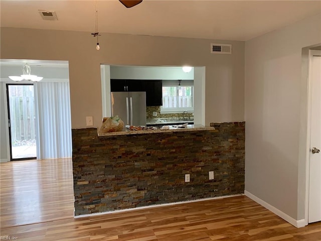 interior space with visible vents, a sink, wood finished floors, and an inviting chandelier