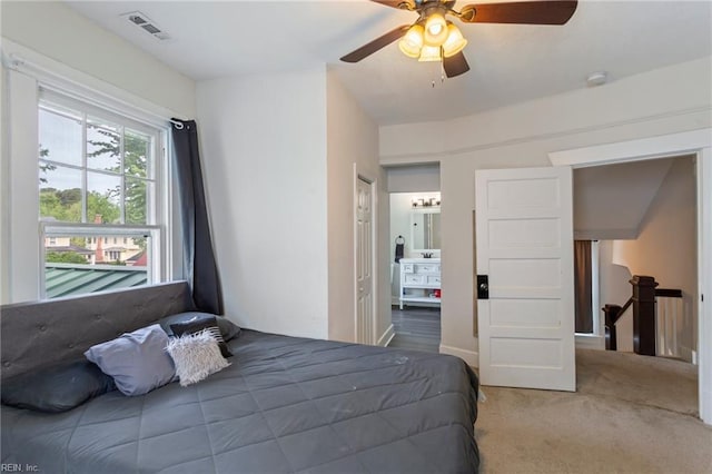 carpeted bedroom with visible vents, ceiling fan, and ensuite bath