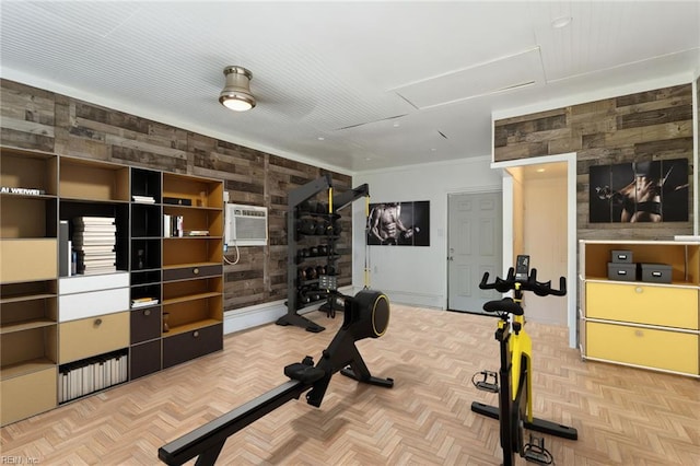 exercise room featuring attic access, a wall mounted AC, crown molding, wooden walls, and baseboards