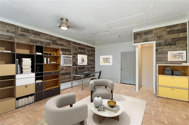 living area with attic access, wooden walls, ornamental molding, and an AC wall unit