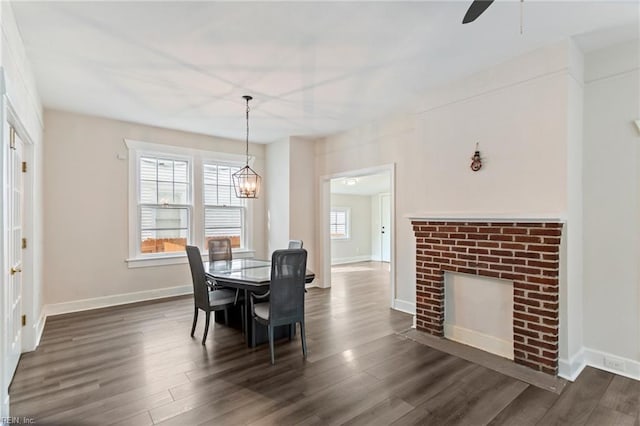 dining space featuring dark wood-style floors, ceiling fan with notable chandelier, and baseboards
