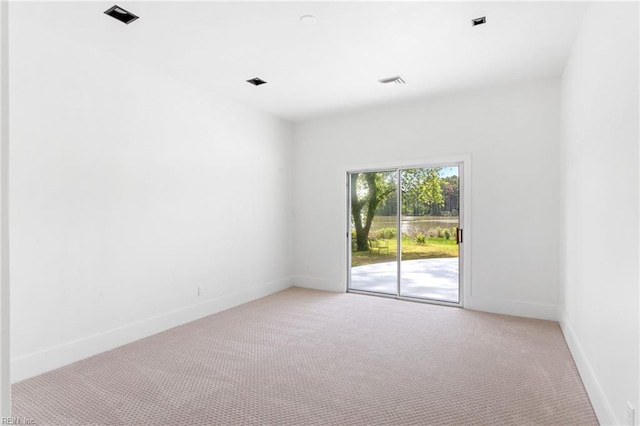spare room with baseboards, visible vents, and light colored carpet