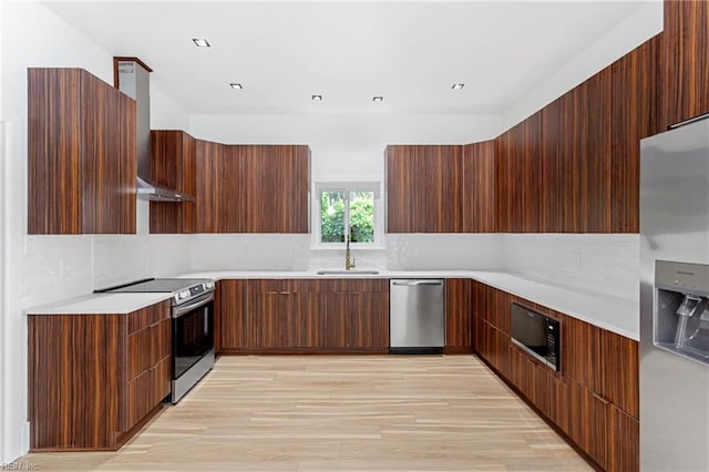 kitchen with tasteful backsplash, stainless steel appliances, a sink, wall chimney exhaust hood, and modern cabinets