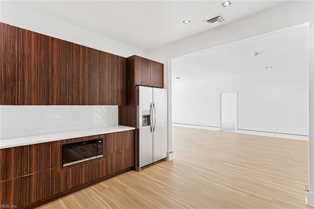 kitchen featuring tasteful backsplash, stainless steel fridge, light wood-style floors, light countertops, and modern cabinets