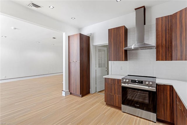 kitchen featuring wall chimney range hood, light countertops, modern cabinets, and stainless steel range with electric cooktop