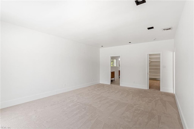 empty room featuring light colored carpet, visible vents, and baseboards