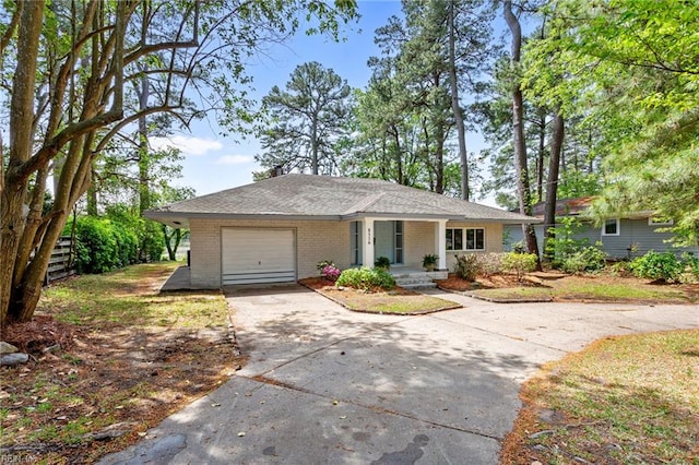 ranch-style home with a porch, concrete driveway, an attached garage, and brick siding