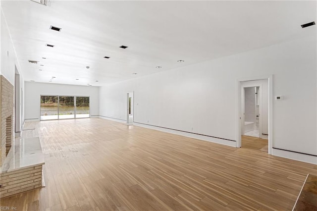 unfurnished living room featuring visible vents, light wood-style flooring, and baseboards