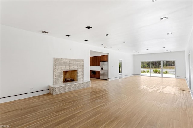 unfurnished living room featuring a fireplace, visible vents, baseboards, and light wood-style floors
