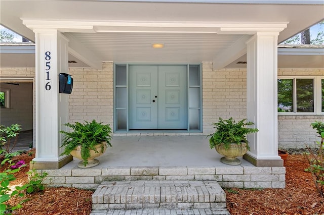 entrance to property featuring a porch and brick siding