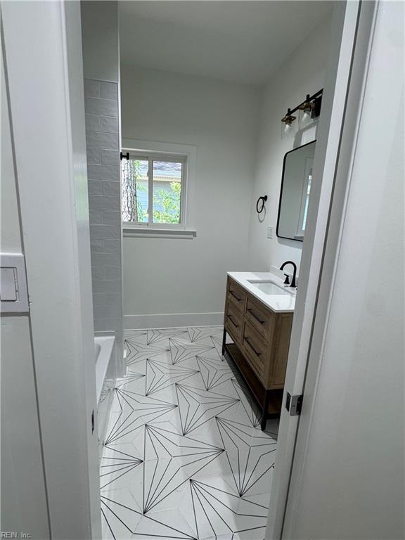 bathroom with a tub to relax in, vanity, tile patterned flooring, and baseboards