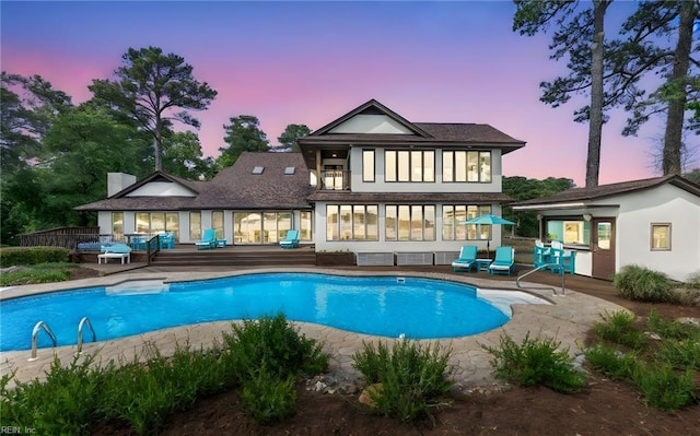 back of house at dusk with a patio and a fenced in pool