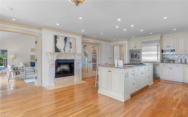 kitchen featuring built in appliances, ornamental molding, backsplash, and light wood finished floors