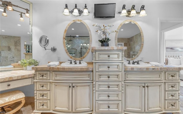 bathroom featuring a sink, walk in shower, and double vanity