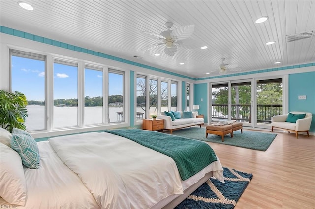 bedroom with access to outside, recessed lighting, a water view, and wood finished floors