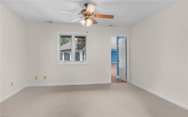 carpeted spare room featuring baseboards, ceiling fan, and visible vents