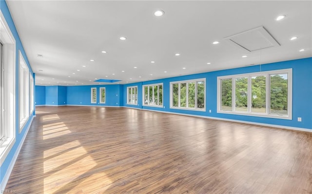unfurnished living room featuring baseboards, attic access, recessed lighting, and wood finished floors
