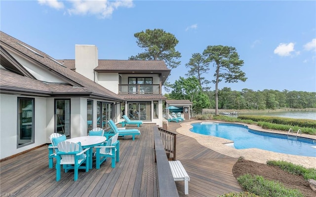 pool featuring a deck with water view and outdoor dining space