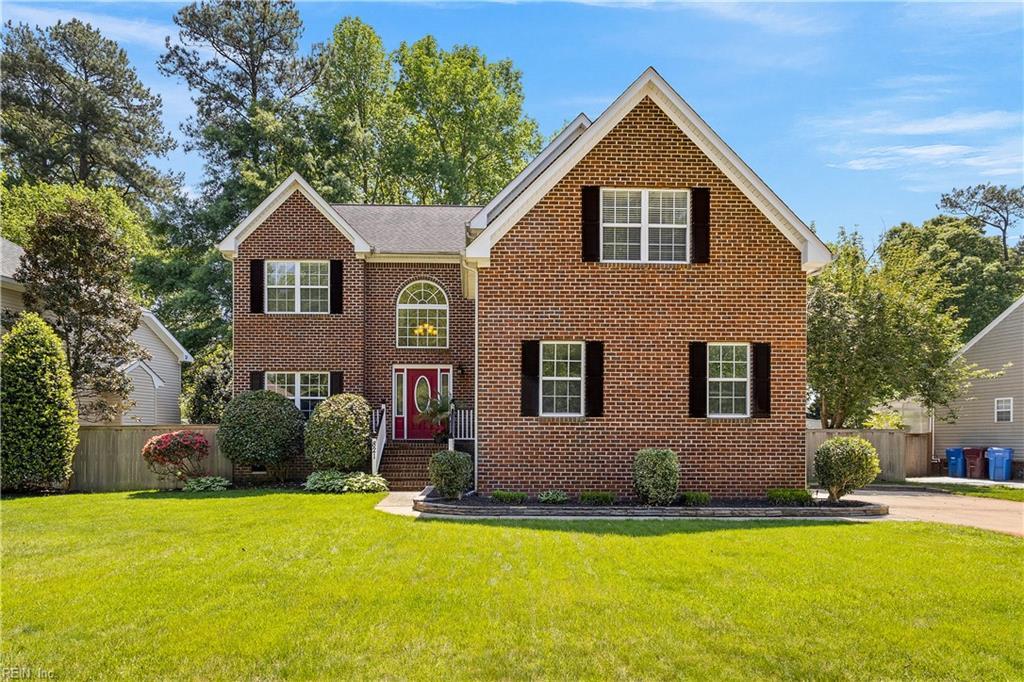 view of front facade featuring brick siding, fence, and a front lawn