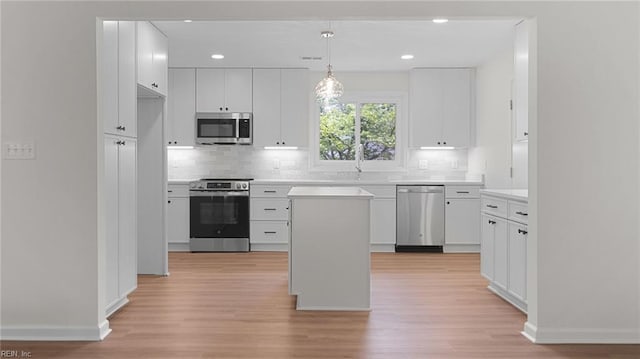 kitchen featuring tasteful backsplash, white cabinets, appliances with stainless steel finishes, and light wood-style floors