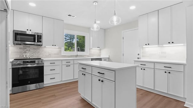kitchen featuring tasteful backsplash, stainless steel appliances, light wood-type flooring, a sink, and visible vents