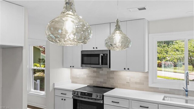 kitchen with appliances with stainless steel finishes, light countertops, a sink, white cabinetry, and visible vents