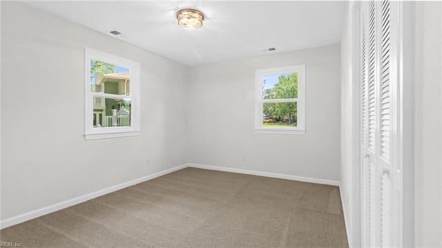 spare room with visible vents, carpet flooring, and baseboards