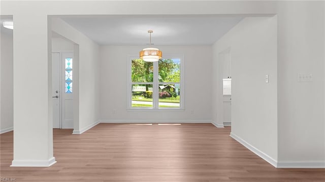 unfurnished dining area featuring light wood-style floors, plenty of natural light, and baseboards