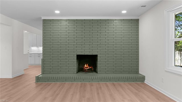 interior details with baseboards, visible vents, wood finished floors, and a fireplace
