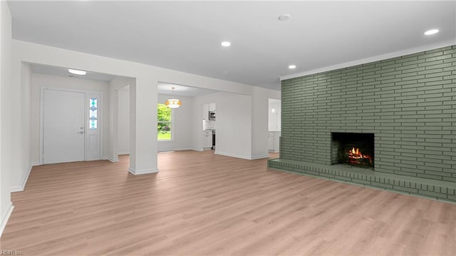 unfurnished living room with baseboards, recessed lighting, a fireplace, and light wood-style flooring