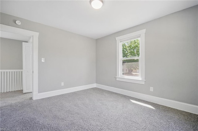 carpeted empty room featuring baseboards