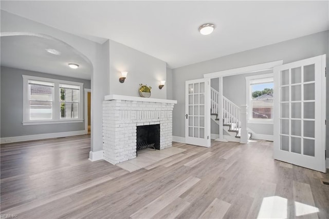unfurnished living room featuring wood finished floors, a healthy amount of sunlight, and baseboards