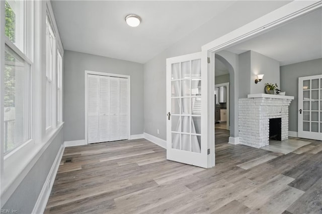 interior space featuring wood finished floors, plenty of natural light, baseboards, and arched walkways