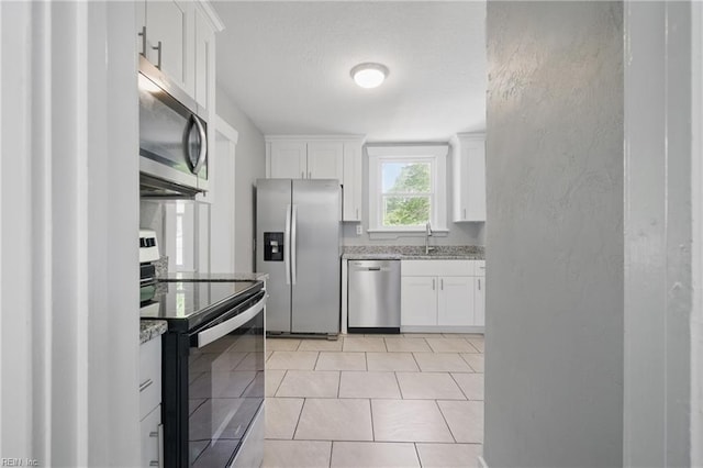 kitchen with stainless steel appliances, light stone countertops, and white cabinets