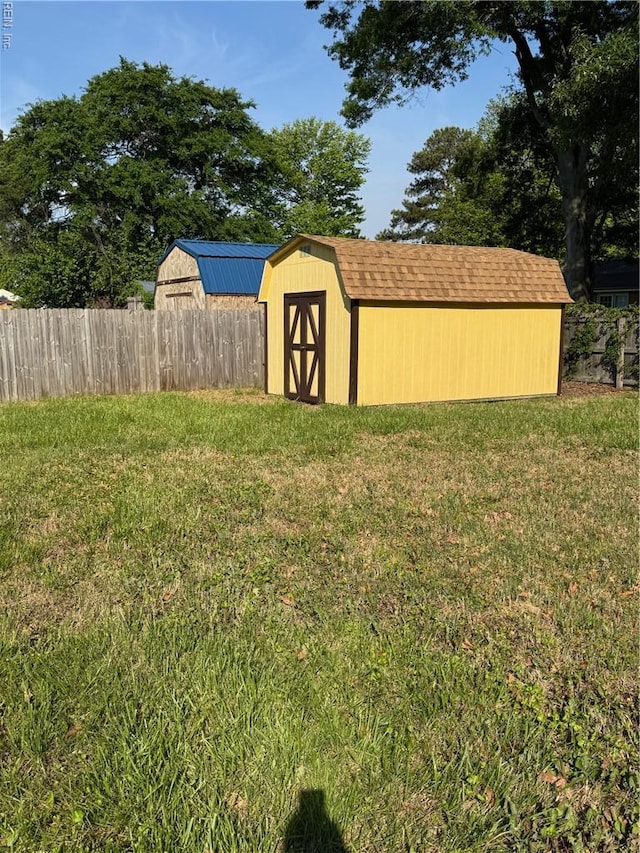 view of yard featuring fence, a shed, and an outbuilding