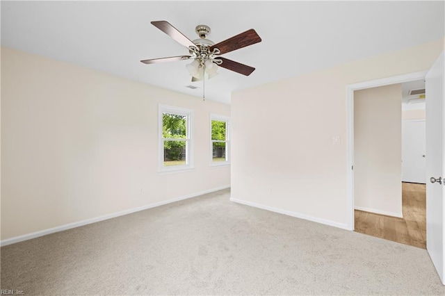 carpeted spare room with visible vents, ceiling fan, and baseboards