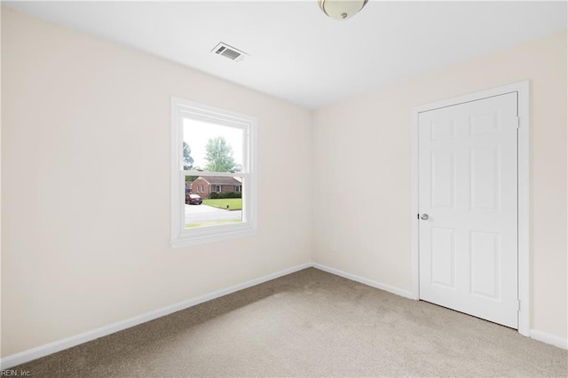 spare room featuring visible vents, light colored carpet, and baseboards