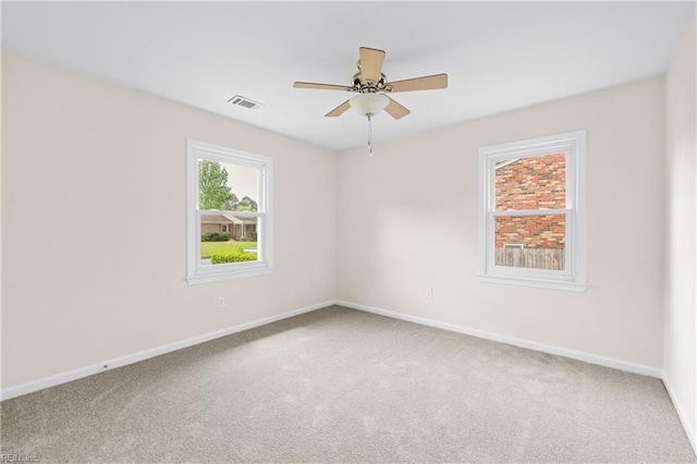 carpeted spare room with visible vents, ceiling fan, and baseboards