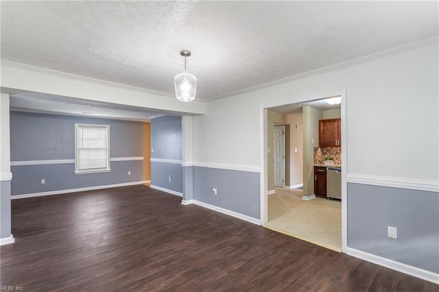 unfurnished room with baseboards, wood finished floors, a textured ceiling, and crown molding