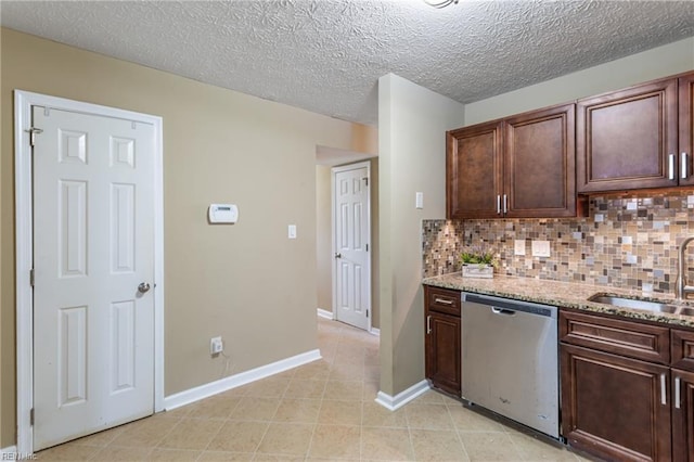kitchen with light stone countertops, stainless steel dishwasher, dark brown cabinets, backsplash, and a sink