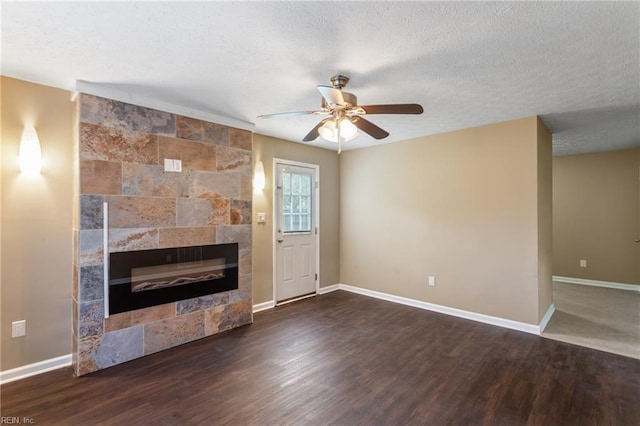unfurnished living room with a textured ceiling, a tiled fireplace, and baseboards