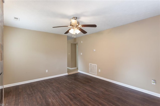spare room with a ceiling fan, visible vents, baseboards, and dark wood-type flooring