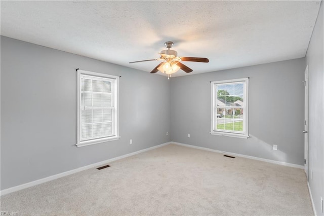 carpeted empty room featuring visible vents, ceiling fan, and baseboards
