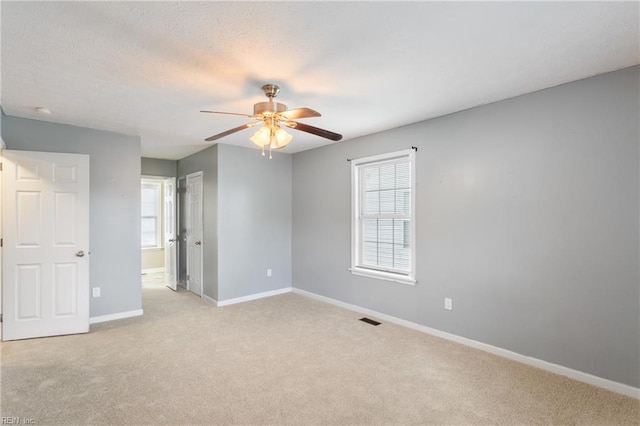 unfurnished bedroom featuring ceiling fan, baseboards, visible vents, and light carpet