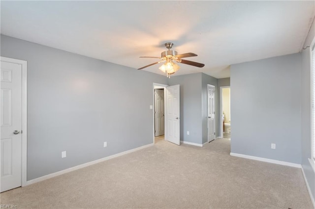 unfurnished bedroom with baseboards, ceiling fan, light carpet, and ensuite bathroom