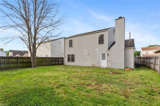 back of house featuring a lawn, a fenced backyard, and a chimney