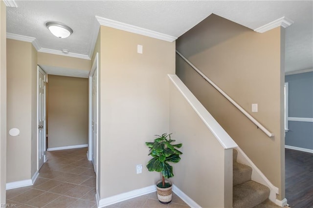 stairs featuring crown molding, tile patterned flooring, a textured ceiling, and baseboards